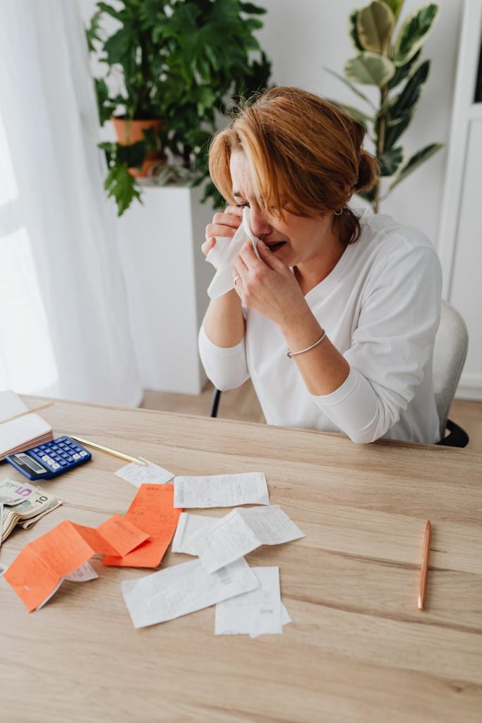House Clearance Budget Hacks: Must-Have Tips for Affordable Salvaging Stressed woman calculating expenses and debt with receipts and bills at home.