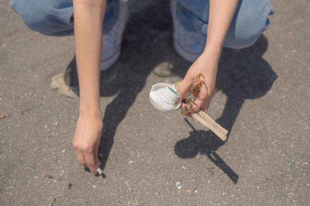 Close-up of a person picking up trash on a sandy beach, promoting environmental care.