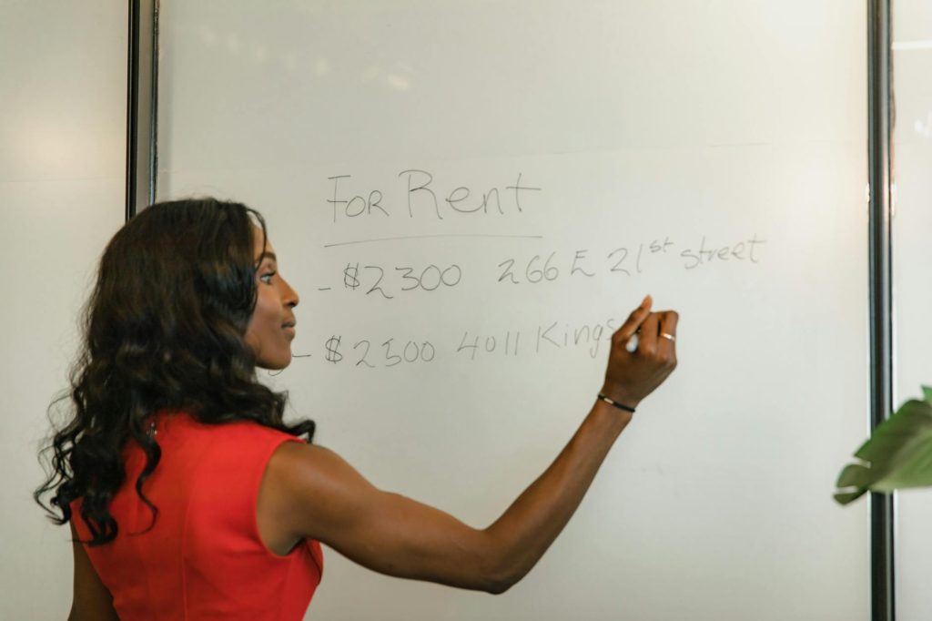 Affordable Office Relocations: 3 Must-Know Hacks for Success Professional woman writing real estate prices on a whiteboard for rental properties.
