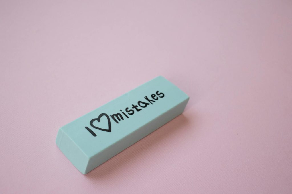 Office Removal Mistakes: Avoid These Costly Blunders Close-up of a mint green eraser with 'I love mistakes' on a pink background.
