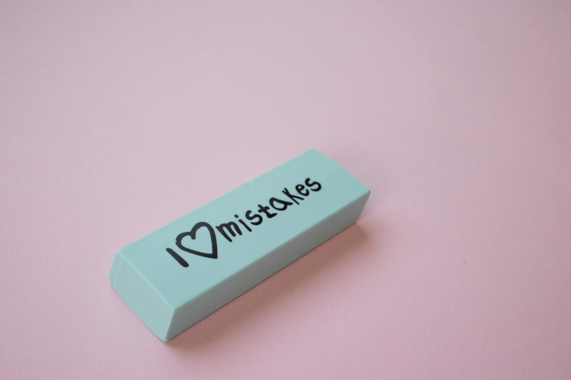 Office Removal Mistakes: Avoid These Costly Blunders Close-up of a mint green eraser with 'I love mistakes' on a pink background.