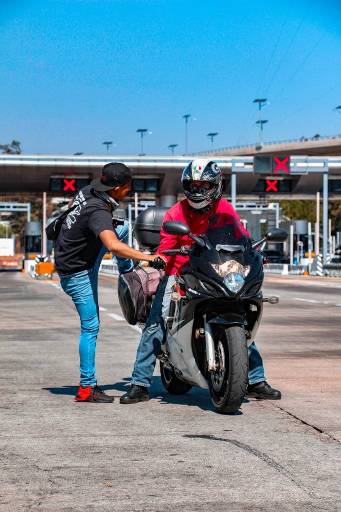 Car Handover Checklist: Must-Have Steps for Effortless Peace of Mind Two men at a toll booth, a motorcyclist receiving a bag from a friend.