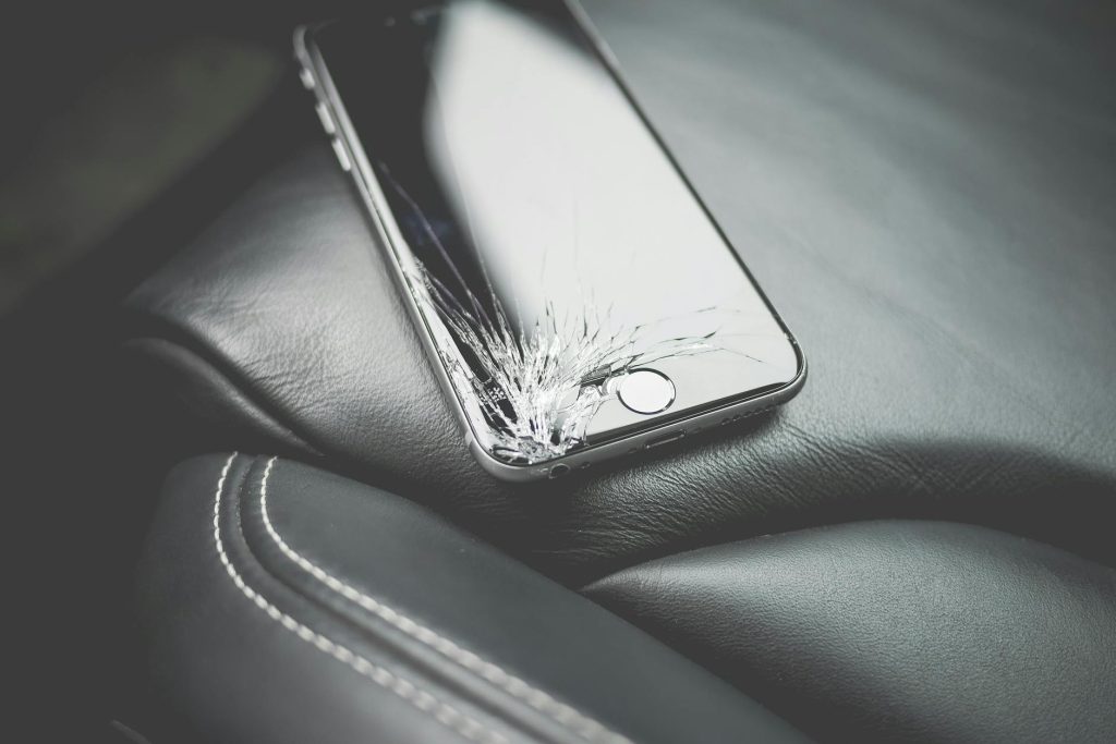 Salvaging Electronics: 4 Expert Tips for Safe Recovery Close-up of a broken smartphone with a cracked screen on a leather car seat.