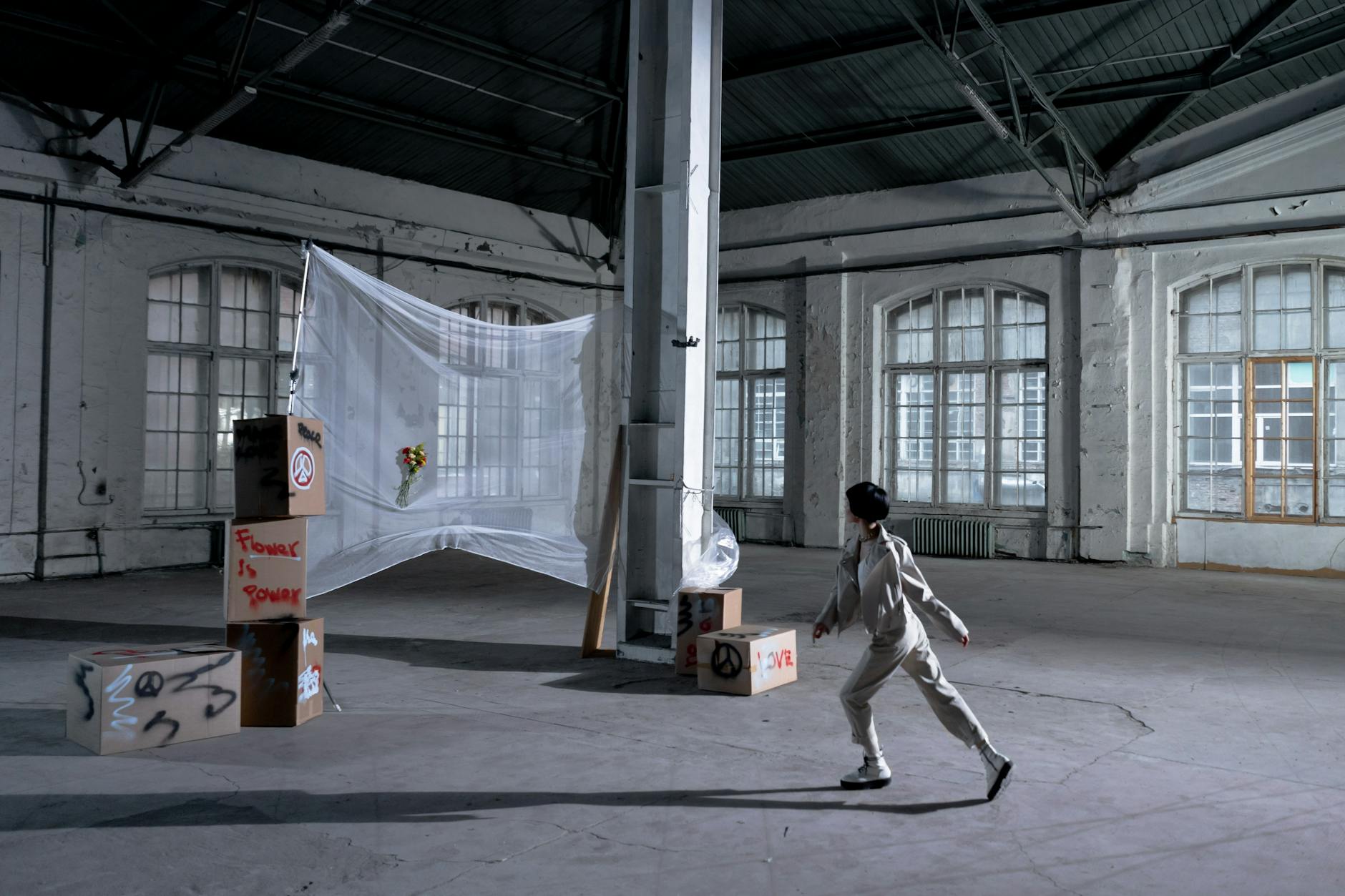 Minimize Industrial Move Disruptions with Effortless Strategies Artistic protest installation in an urban warehouse setting with a person observing.