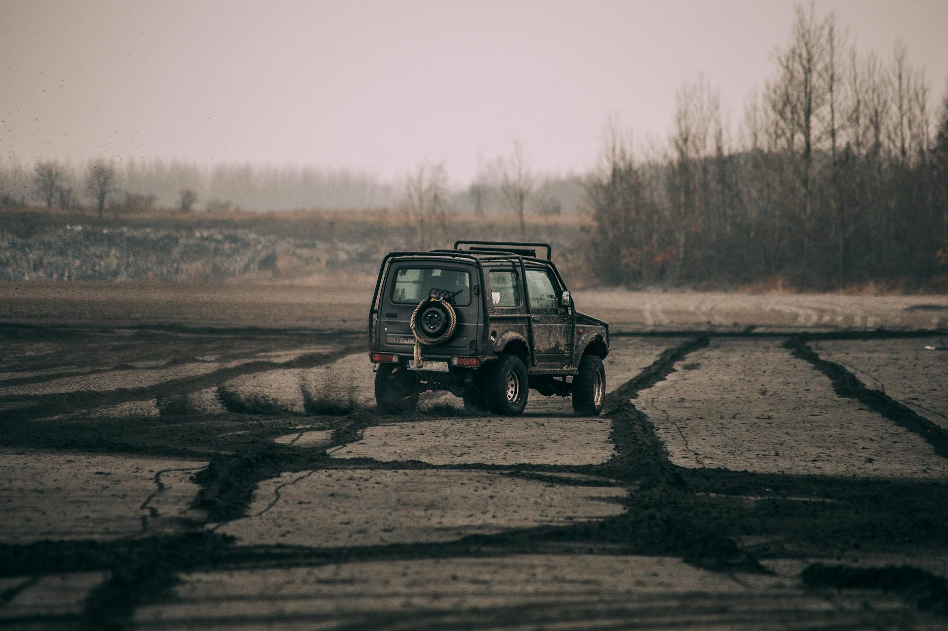 Car Shipping: Effortless Ways to Track Your Vehicle SUV navigating through muddy terrain in a misty setting, showcasing adventure.