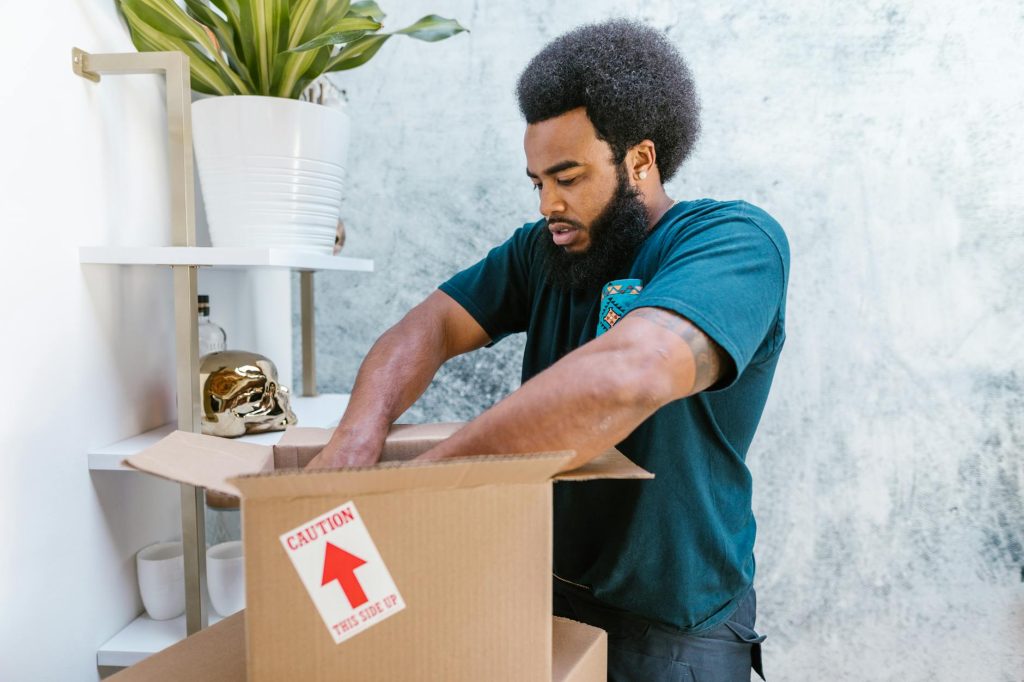Moving a Small Business: 5 Affordable and Effective Budget-Friendly Tips A professional mover packs a fragile item into a box in a stylish room.