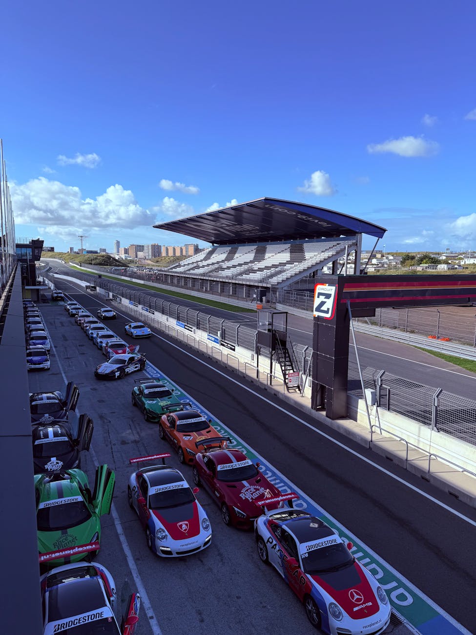 Car Shipping with F1 Removals: 5 Compelling Reasons to Trust Colorful race cars lined up at Circuit Zandvoort on a sunny day, ready for action.