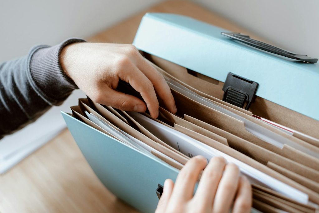 Office Relocations: 5 Compelling Reasons F1 Removals Stands Out Close-up of hands organizing papers in a blue folder, ideal for business and office concepts.