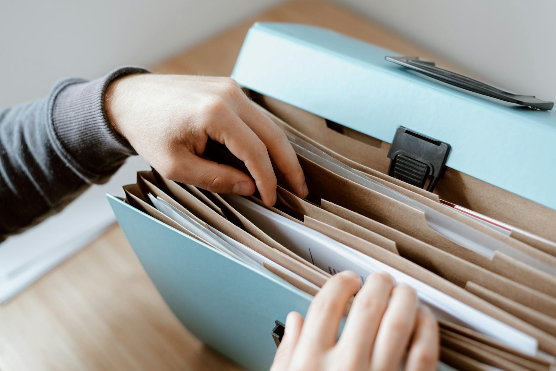 Office Relocations: 5 Compelling Reasons F1 Removals Stands Out Close-up of hands organizing papers in a blue folder, ideal for business and office concepts.