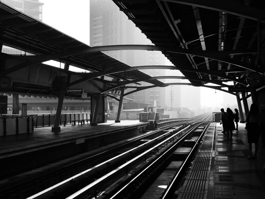 Industrial Move on a Budget: 5 Effortless Tips for Streamlining Silhouettes of people waiting at an urban railway station.