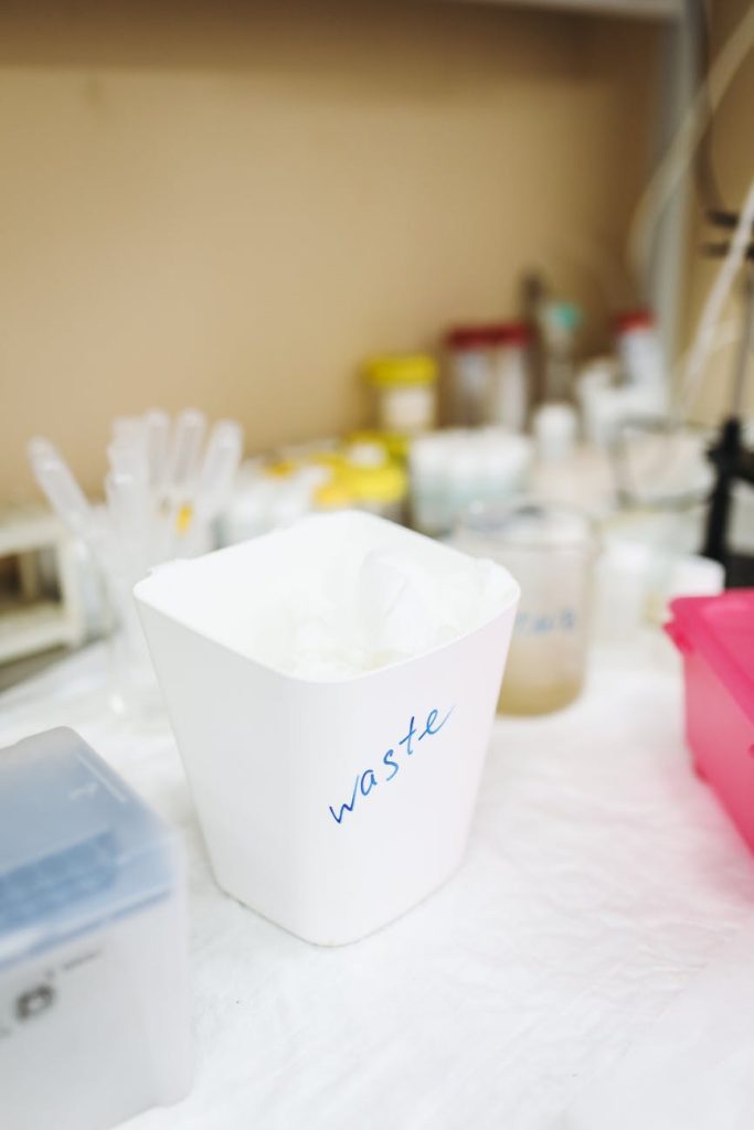 Decluttering Hacks: Effortless Tips to Streamline Waste Removal White waste bin in a laboratory setting, surrounded by glassware and containers.