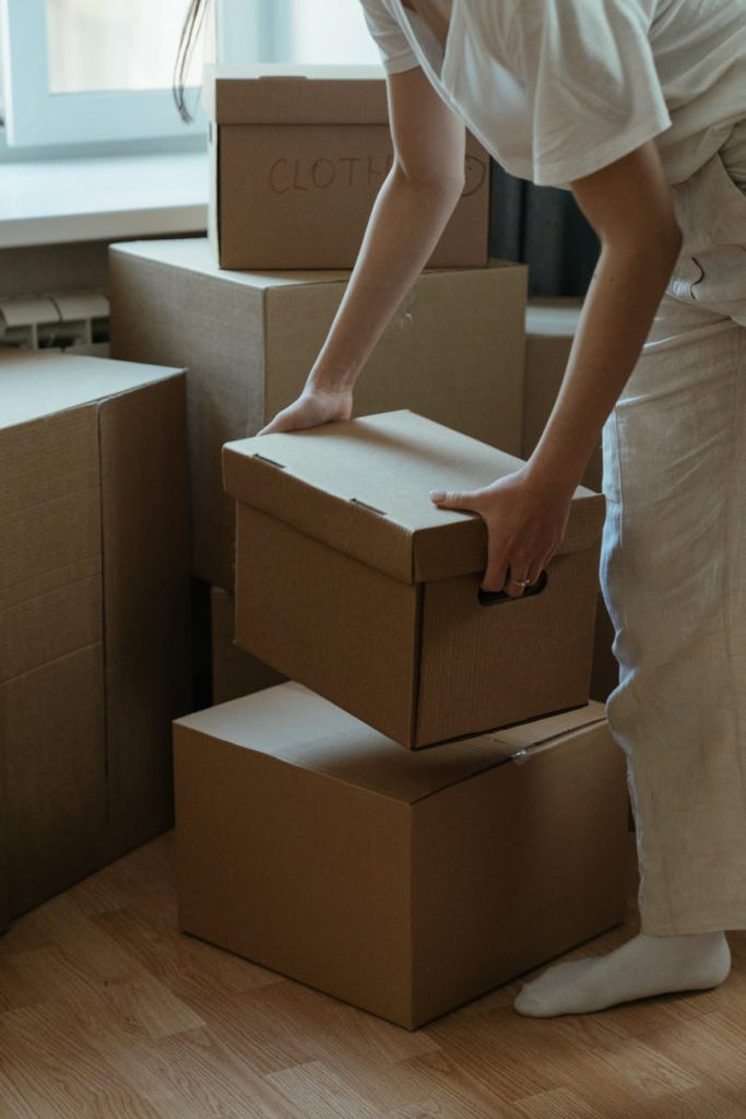 A woman packing cardboard boxes in her new apartment, symbolizing moving and relocation.