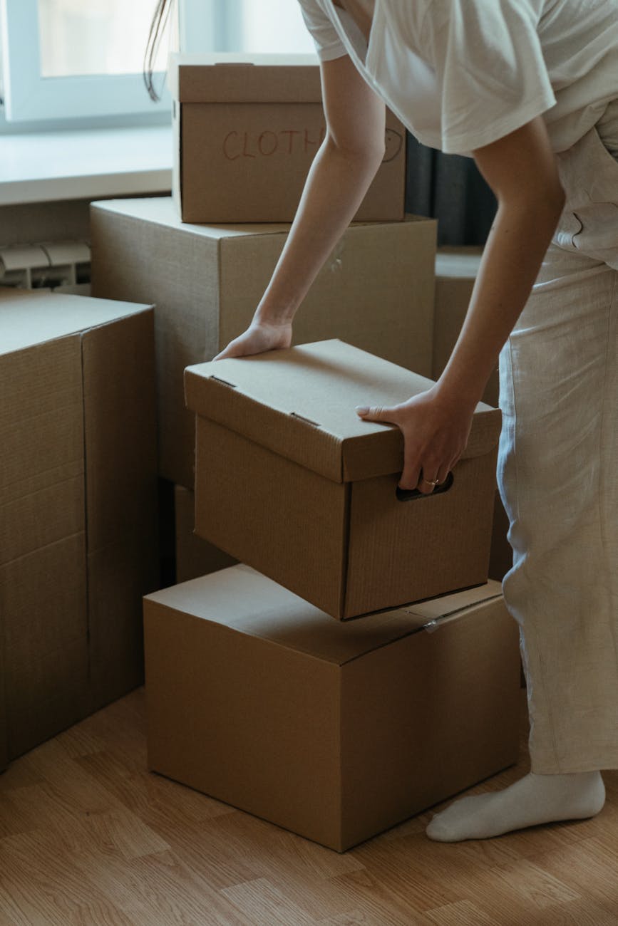 Waste Removal Before a Move: Effortless 6-Step Guide A woman packing cardboard boxes in her new apartment, symbolizing moving and relocation.