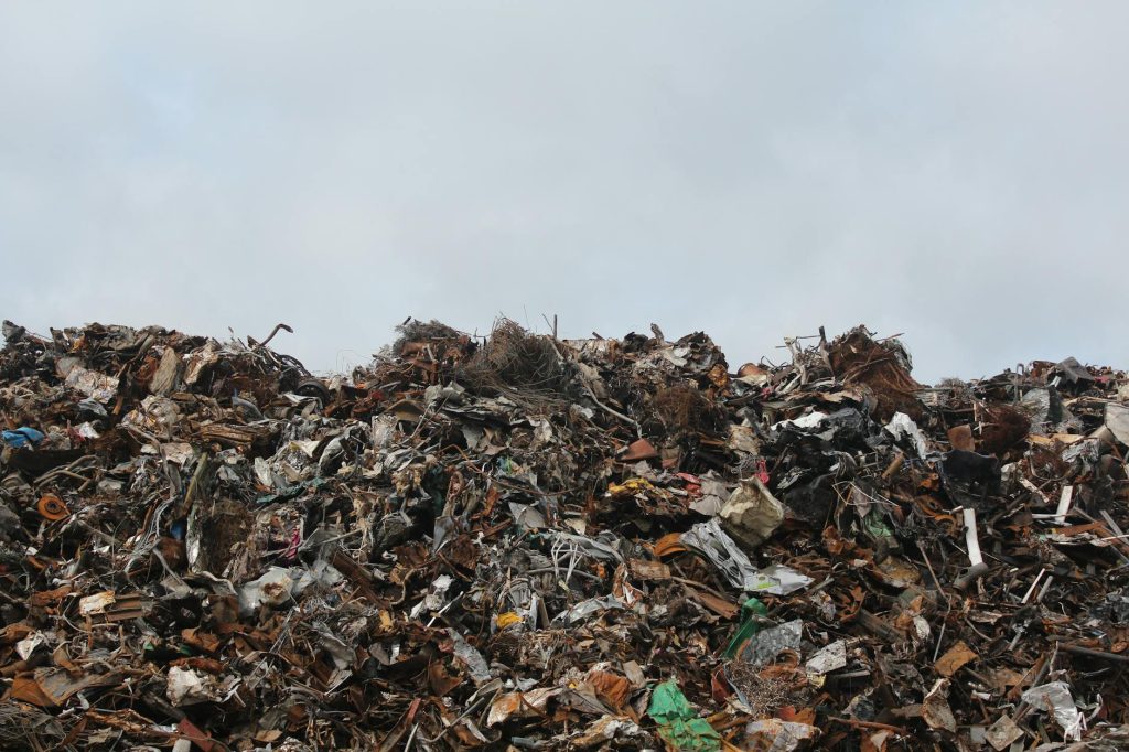 Eco-Conscious Salvage: 6 Must-Have Tips for Effortless Recycling A large pile of scrap metal and waste at a landfill against a cloudy sky.