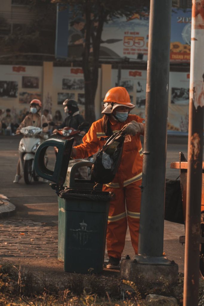 2025 Waste Removal Service: Best Tips for Effortless Selection A sanitation worker in an orange suit empties a trash can on a city street.