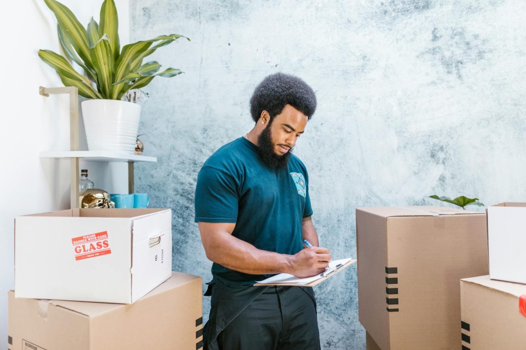 Office Move Checklist: Effortless Planning Tips with F1 Removals A mover with a clipboard checking packages and boxes for relocation indoors.