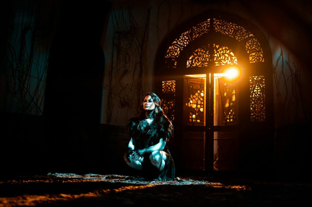 Identifying Salvageable Items for Quick Resale: Top Secrets Revealed A woman in black attire kneels in dramatic lighting with ornate door backdrop.