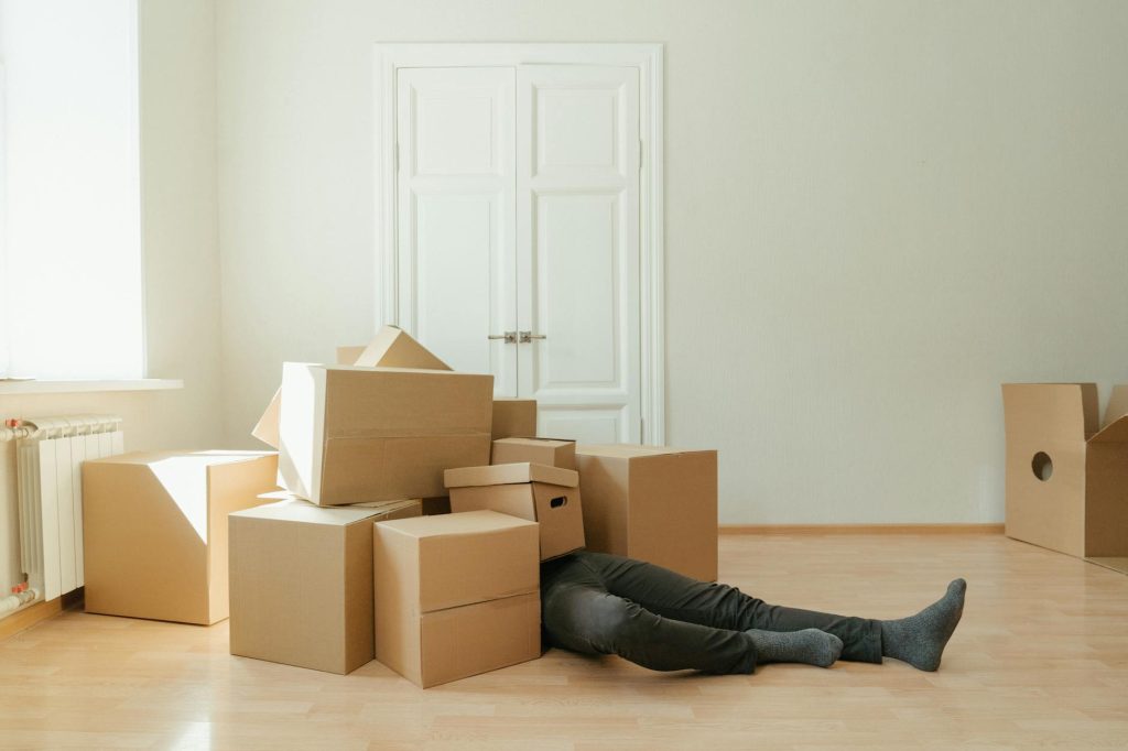 2025 Pro Packing Tips: Effortless Home Organization Person on floor surrounded by cardboard boxes during moving; concept of stress and relocation.