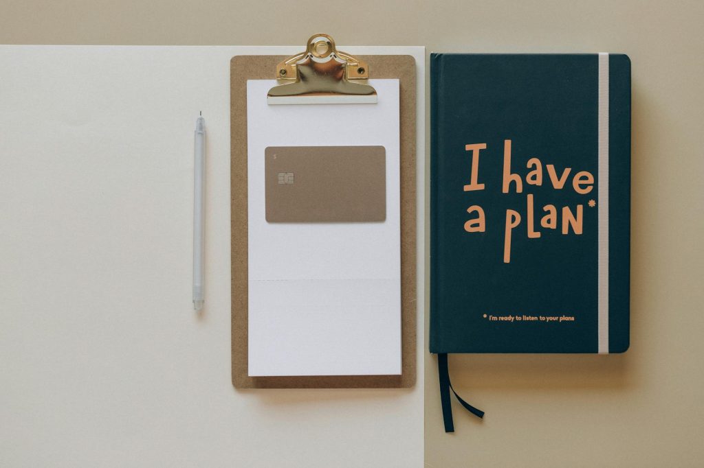 Office Move: Effortless Strategies to Boost Productivity A minimalist office setup featuring a planner, clipboard, card, and pen, perfect for planning and organization.