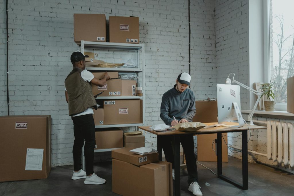Safely Pack Salvaged Items for Transport: Effortless Tips for Success Two workers handling packages and organizing stock in a warehouse setting.