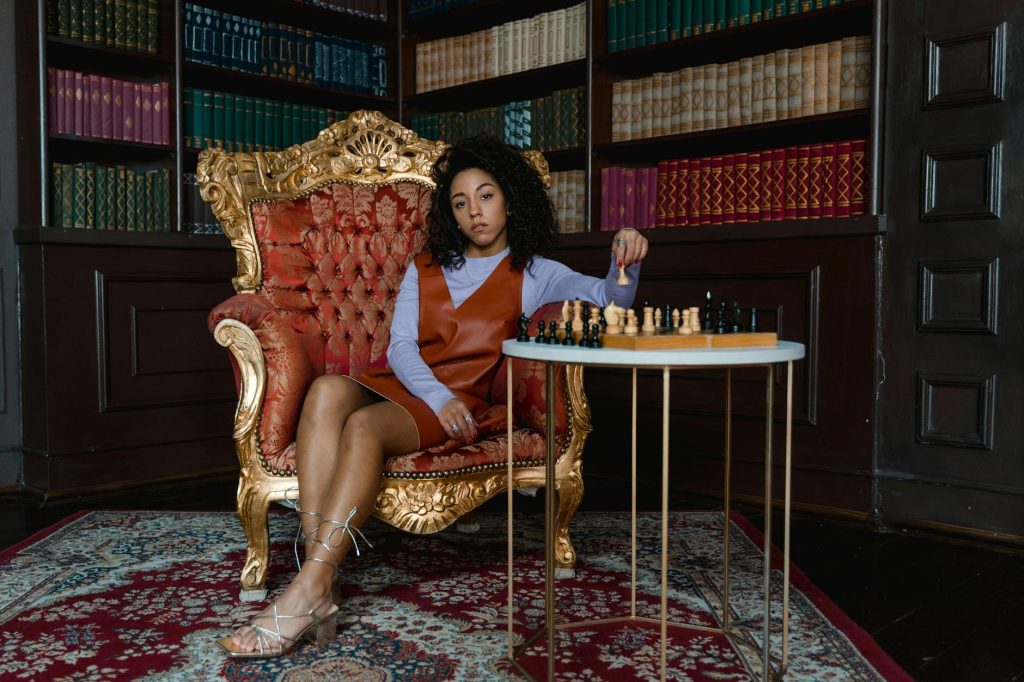 Safely Salvage Antiques: Essential Tips for a Seamless Move Elegant woman in a vintage armchair playing chess in a classic library. A moment of strategy and reflection.
